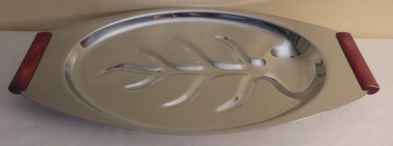 May include: A silver serving tray with wooden handles. The tray has a leaf design cut out of the centre.