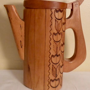 May include: A wooden pitcher with a carved tulip design. The pitcher has a hinged lid and a handle.