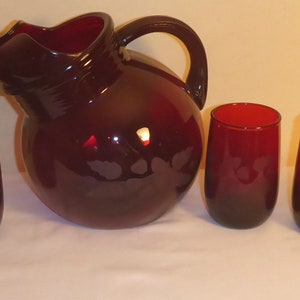 Peut inclure: Un ensemble de six verres à boire en verre rouge rubis et un pichet assorti avec un motif floral. Le pichet a une large ouverture et une poignée.
