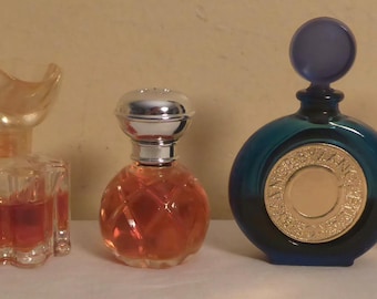 May include: Five vintage perfume bottles of varying shapes and sizes. The bottles are filled with amber and red-hued liquids. The bottles have decorative stoppers and labels. The bottles are arranged in a row, showcasing their unique designs and colors.