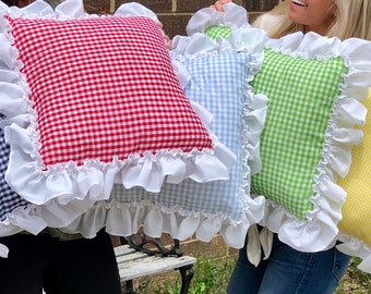May include: Four decorative throw pillows with gingham patterns in blue, red, green, and yellow. Each pillow has a white ruffle trim.