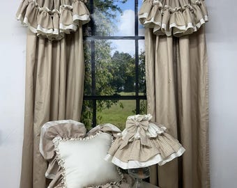 May include: A set of beige curtains with a brown and white gingham valance featuring ruffled edges, a square white pillow with a ruffled gingham border, and a lamp with a matching gingham ruffled shade, all displayed on a round table.