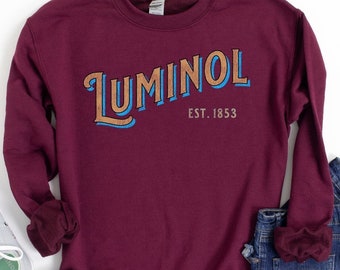 May include: A maroon sweatshirt with a vintage-style graphic that says "Luminol Est. 1853" in brown and blue lettering.