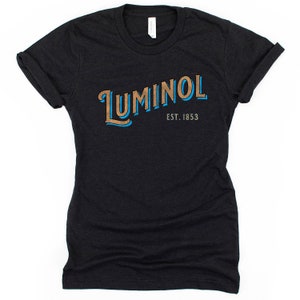 May include: Black t-shirt with a blue and brown graphic that says "LUMINOl EST. 1853"