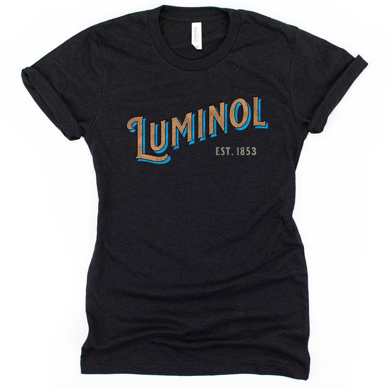 May include: Black t-shirt with a blue and brown graphic that says "LUMINOl EST. 1853"