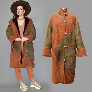 May include: A long, patchwork coat in shades of brown and olive green. The coat features wooden toggle closures and a high collar. The design includes geometric panels and a warm, textured appearance, suggesting a vintage or bohemian style.