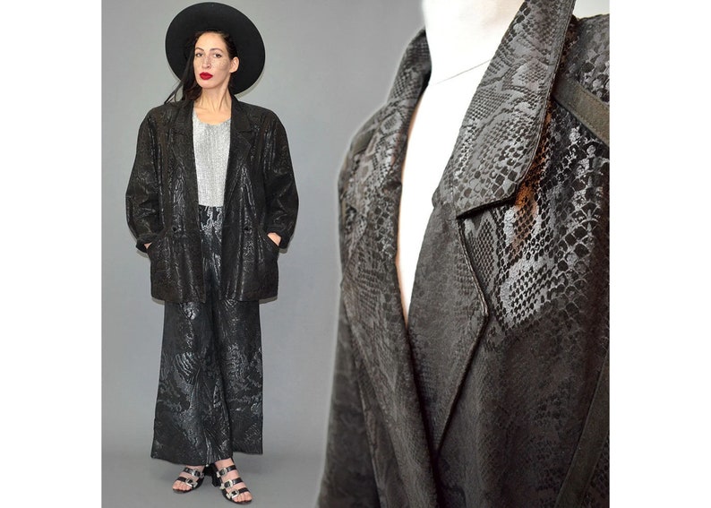 May include: A black blazer and matching wide-leg trousers set featuring a tonal snakeskin pattern. The blazer has a notched lapel, long sleeves, and two front pockets. The trousers are high-waisted with a loose, flowing silhouette throughout.