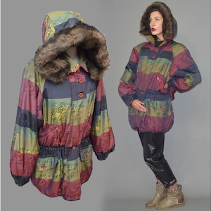 May include: A white ceramic mug with a black handle and the text "But First, Coffee" in a bold, black font. The mug is set against a blurred background, suggesting a cosy setting.