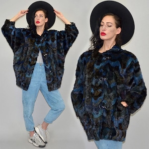 Puede incluir: Un abrigo vintage de piel sintética en tonos azules, negros y marrones. El abrigo presenta un patrón de chevrón único, cierre de botón y bolsillos. La modelo lleva un sombrero negro y pantalones azul claro.