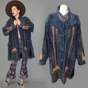Può includere: Un cappotto vintage in camoscio blu con colletto in pelle nera e chiusura con bottoni. Il cappotto presenta disegni astratti verticali nelle tonalità del marrone e del verde. Il cappotto è esposto su un manichino e indossato da una persona.
