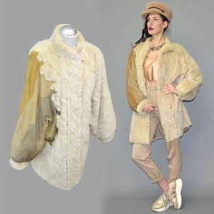 Op de afbeelding: Een vintage crèmekleurige bontjas met een uniek design. De jas heeft een patchwork van bruin suède op de mouwen en schouders. De jas wordt getoond op een mannequin en gedragen door een persoon.