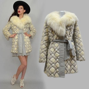 Puede incluir: Abrigo de piel vintage con cuello de piel de zorro color crema y cuerpo con estampado de diamantes a juego. El abrigo presenta un cinturón de lazo gris y un forro gris claro. El abrigo es hasta la rodilla y tiene mangas largas.