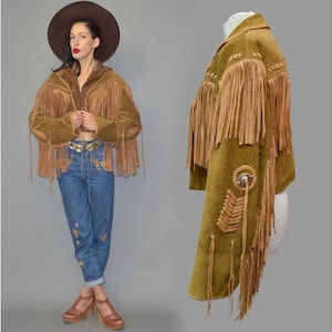 Peut inclure: Veste en daim avec de longues franges marron et vert olive. La veste présente des coutures décoratives et des ornements. Vêtement d'inspiration western vintage.
