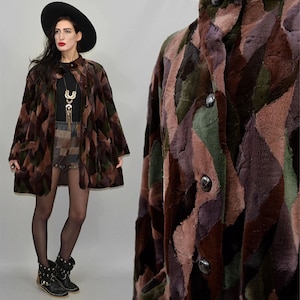 May include: A vintage coat with a patchwork design in shades of brown, green, and purple. The coat features a button-up front and a collarless design. The coat is knee-length and has a unique, textured appearance.