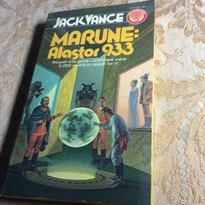 Pode incluir: Uma capa de romance de ficção científica de bolso com fundo amarelo. O título é "Marune: Alastor 933" e o autor é "Jack Vance". A arte da capa representa um grupo de pessoas em pé em uma sala com um grande orbe brilhante no centro.