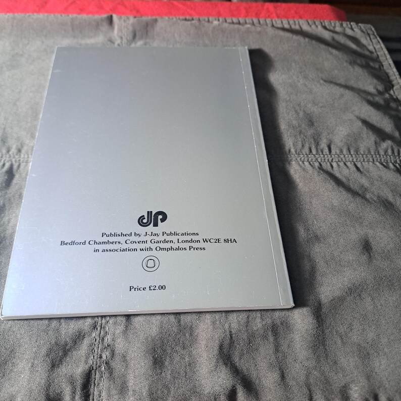 May include: A silver book with text from J-Jay Publications, Bedford Chambers, Covent Garden, London WC2E 8HA, in association with Omphalos Press. The book is on a grey surface.