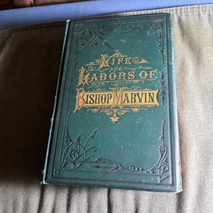 May include: A green hardback book with gold lettering on the front cover. The title is "Life and Labors of Bishop Marvin".