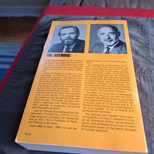 May include: A vintage book cover featuring portraits of two men, with text detailing their research on radioactivity and its effects. The cover is yellow and white with blue text.