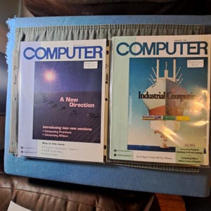 Puede incluir: Dos portadas de revistas "COMPUTER" vintage. El número de diciembre presenta una escena desértica con el texto "A New Direction". El número de enero muestra una ilustración de un barco con las palabras "Industrial Computing".