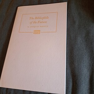 May include: A pale pink book cover with the title "The Bibliophile of the Future" by Jacques Barzun in gold lettering.