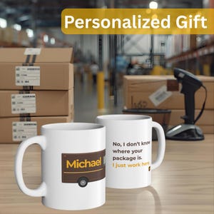 May include: Two white ceramic mugs. One mug features a brown and yellow design with the name "Michael" and a truck illustration. The other mug has the text "No, I don't know where your package is. I just work here."
