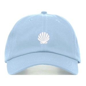 Puede incluir: Una gorra de béisbol azul claro con una concha blanca bordada en la parte delantera.