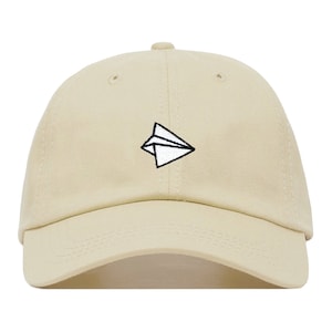 May include: A beige baseball cap with a white paper airplane embroidered on the front.