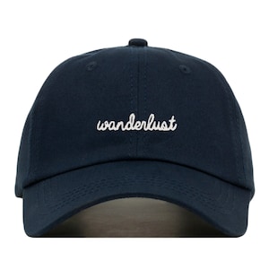 Puede incluir: Una gorra de béisbol azul marino con texto bordado en blanco que dice "wanderlust".