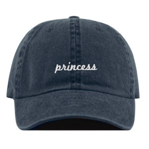 May include: A dark blue denim baseball cap with the word "princess" embroidered in white on the front.