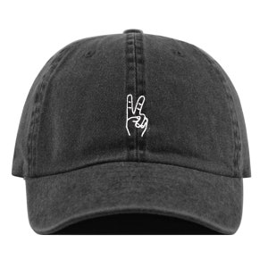 May include: A black denim baseball cap with a white embroidered peace sign.