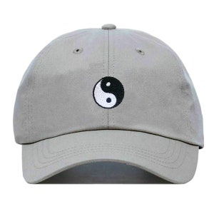 Könnte beinhalten: Eine graue Baseballkappe mit einem schwarzen und weißen Yin-Yang-Symbol, das auf der Vorderseite gestickt ist.