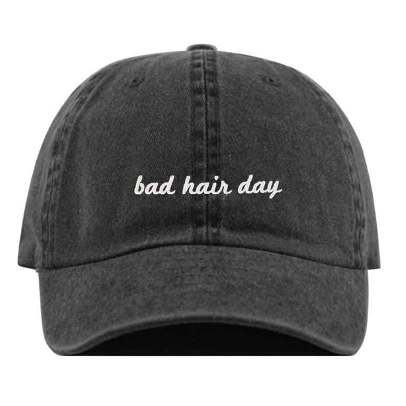 May include: A black denim baseball cap with white embroidered text that reads "bad hair day".