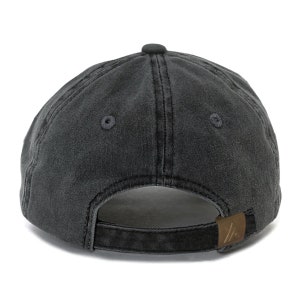 May include: A black, washed cotton baseball cap with a brown leather adjustable strap and a small logo on the back.