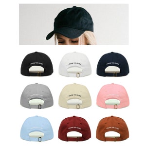May include: Ten different color baseball caps with the text "YOU'RE TOO CLOSE" embroidered in white on the front of each cap.