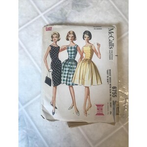 May include: Vintage McCall's sewing pattern for misses' dresses with slim or full skirts. The pattern features illustrations of three dresses: a polka-dot dress, a patterned dress, and a yellow dress. The pattern is labeled "Easy to Sew."