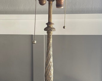 May include: A gold-toned table lamp with a marble base and ornate details. The lamp has a decorative finial and two pull chains.
