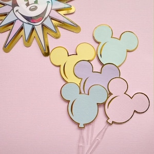 Pu&ograve; includere: Cinque topper per torta a forma di palloncino Mickey Mouse in colori pastello con contorni dorati. I palloncini sono in tonalit&agrave; di azzurro, rosa, giallo e viola.