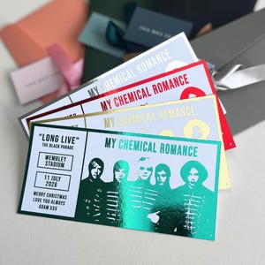 May include: A stack of concert tickets with the text "MY CHEMICAL ROMANCE" in various metallic colors. One ticket features the text "LONG LIVE" and "WEMBLEY STADIUM" with a date of "11 JULY 2026". The tickets are on a white background.