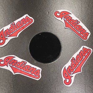 May include: Four red and blue "Indians" decals on a gray surface. The decals are in a stylized font and have a curved shape.