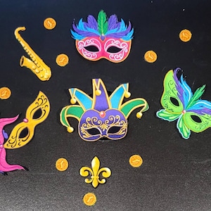May include: A set of Mardi Gras themed party decorations featuring a purple, green, and gold fleur-de-lis, a gold trumpet, and five colorful masks. The masks are a butterfly, a jester, and three traditional Venetian masks.