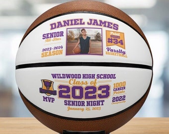 May include: A personalized basketball with a white background and brown leather texture. It features a purple and gold Wildwood High School logo, the text "Class of 2023 Senior Night January 25, 2023", and a photo of a basketball player with the name "Daniel James" and the text "Point Guard #34 Varsity Basketball".