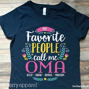 May include: Navy blue t-shirt with a floral design and the text "MY Favorite PEOPLE call me OMA" in pink, white, and yellow. The names "KELLY SARAH SAMUEL MADISON" are printed below in pink.
