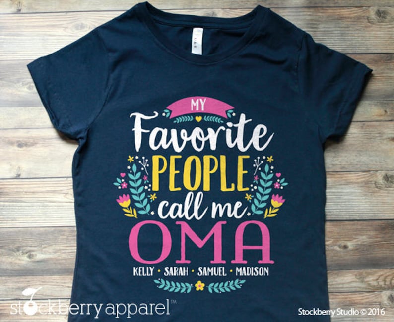 May include: Navy blue t-shirt with a floral design and the text "MY Favorite PEOPLE call me OMA" in pink, white, and yellow. The names "KELLY SARAH SAMUEL MADISON" are printed below in pink.