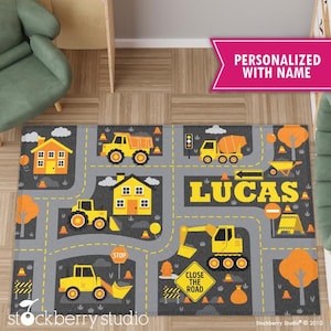 May include: A gray and yellow construction themed play rug with a personalized name "LUCAS" in yellow letters. The rug features illustrations of construction vehicles, traffic signs, and buildings.