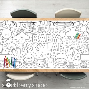 May include: A black and white colouring table runner featuring a baby shower theme with the name "Baby Skylar" and various baby-related illustrations. The runner is designed for colouring with crayons or markers.