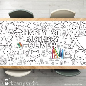 May include: A black and white coloring table cover featuring a woodland theme with animals, trees, a tent, a campfire, and the text "HAPPY 1ST BIRTHDAY OLIVER".