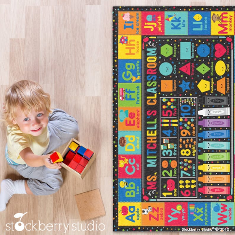 May include: A black and white alphabet and number learning rug with colorful illustrations and text. The rug features the letters A through Z, the numbers 1 through 10, and various shapes. The text on the rug reads "Ms. Mitchell's Classroom".