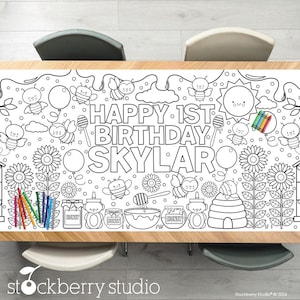 May include: A black and white coloring table cloth with a bee and honey theme. The text "Happy 1st Birthday Skylar" is printed on the tablecloth.