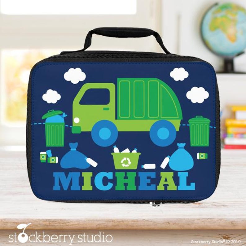 Puede incluir: Una bolsa de almuerzo azul marino con un cami&oacute;n de basura verde, nubes blancas y s&iacute;mbolos de reciclaje. El nombre "MICHEAL" est&aacute; impreso en verde y azul. Tiene un asa y cremallera negras.