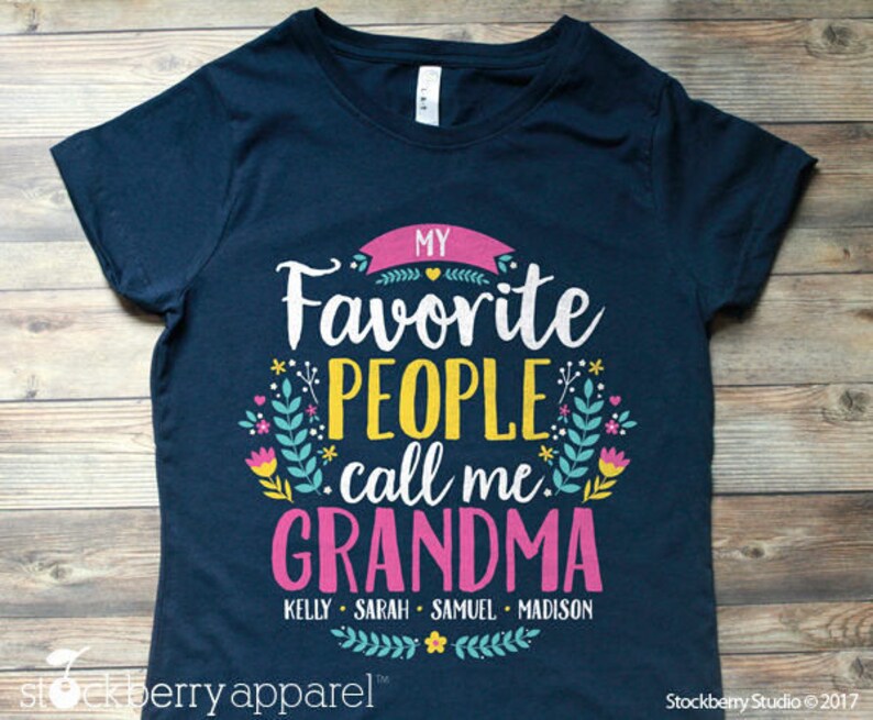 May include: Navy blue t-shirt with a pink and yellow graphic that says "My Favorite People Call Me Grandma" with the names Kelly, Sarah, Samuel, and Madison underneath.
